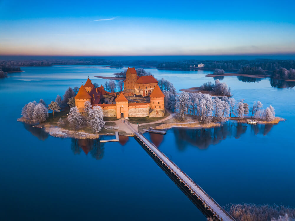 Ein großes Schloss mit Schnee mitten in einem See im Winter im Baltikum