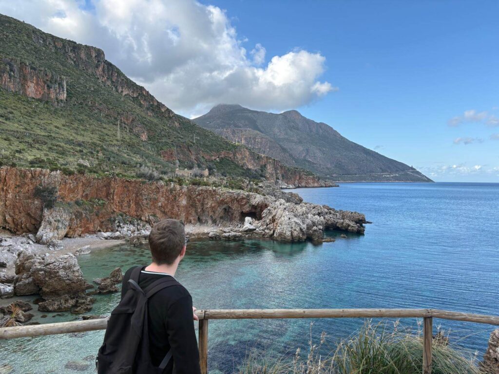 Junger Mann schaut auf eine wunderschöne Bucht in einem Naturschutzgebiet in Sizilien
